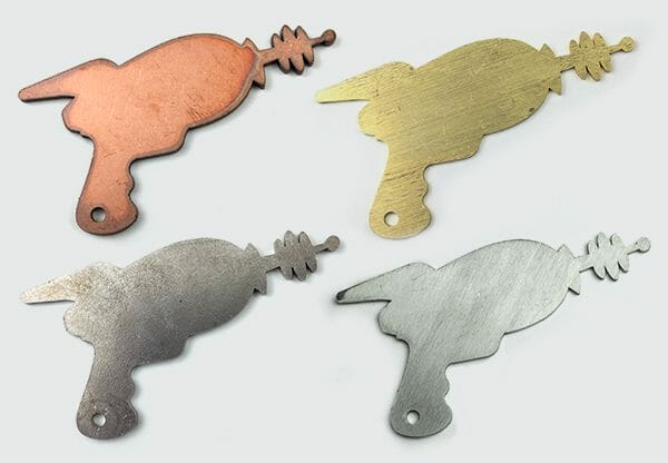 Image showing four laser gun parts in four of the different metals SendCutSend offers for their laser cutting service