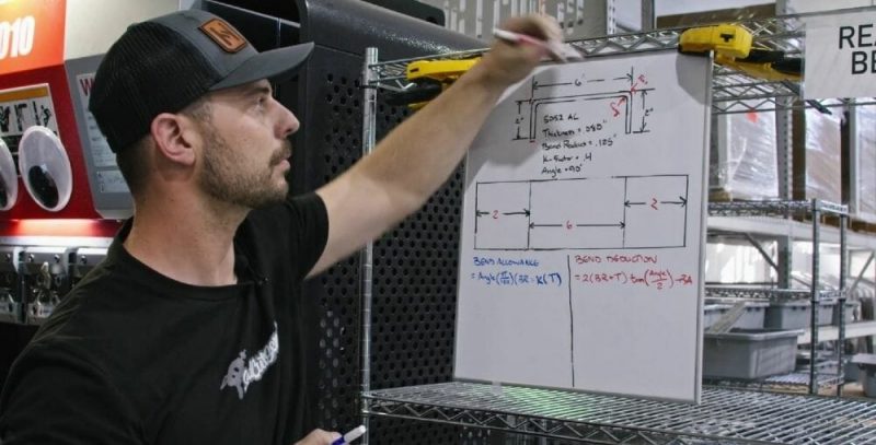 Screenshot of the Video Guide with Jake in front of a white board, drawing the tension and compression in the apex of a bend. 
