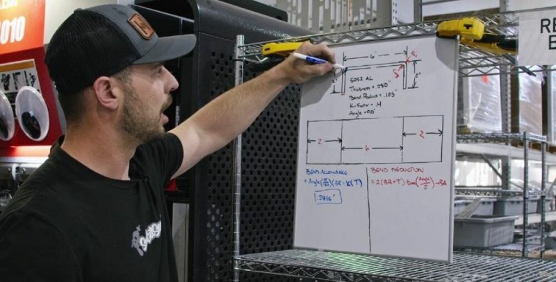 Screenshot of the Video Guide with Jake in front of a white board showing where the neutral axis is in a bend and a completed bend allowance equation.
