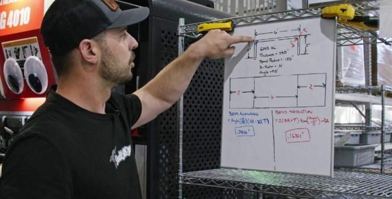 Screenshot of the Video Guide with Jake in front of a white board showing where the neutral axis is in a bend and a completed bend allowance and bend deduction equation.