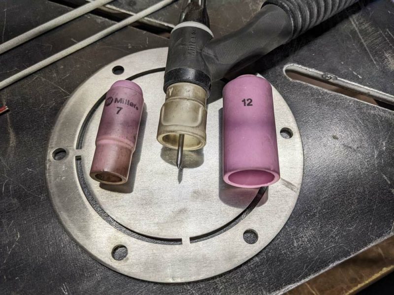 Image of a tig welding torch with two different pink torch cups, sizes 7 and 12.